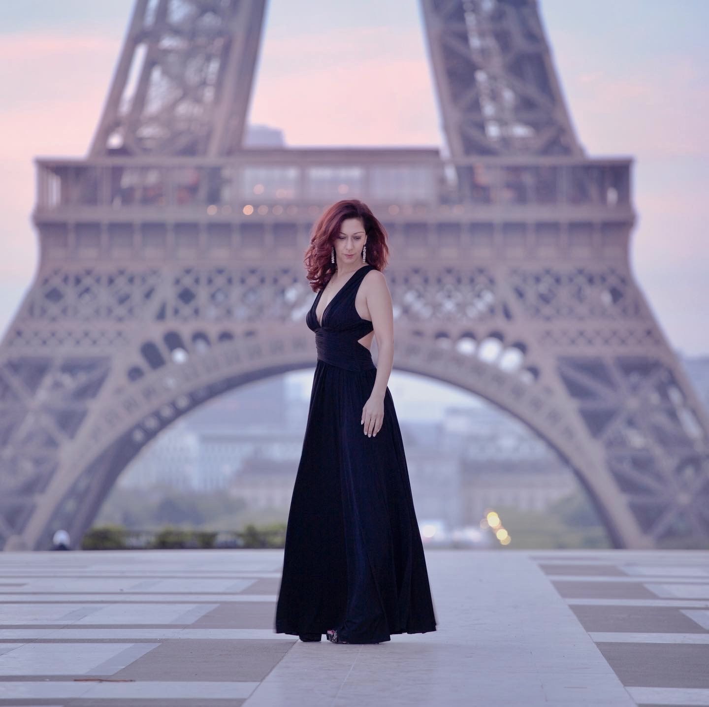 Woman in a black gown standing in front of the Eiffel Tower