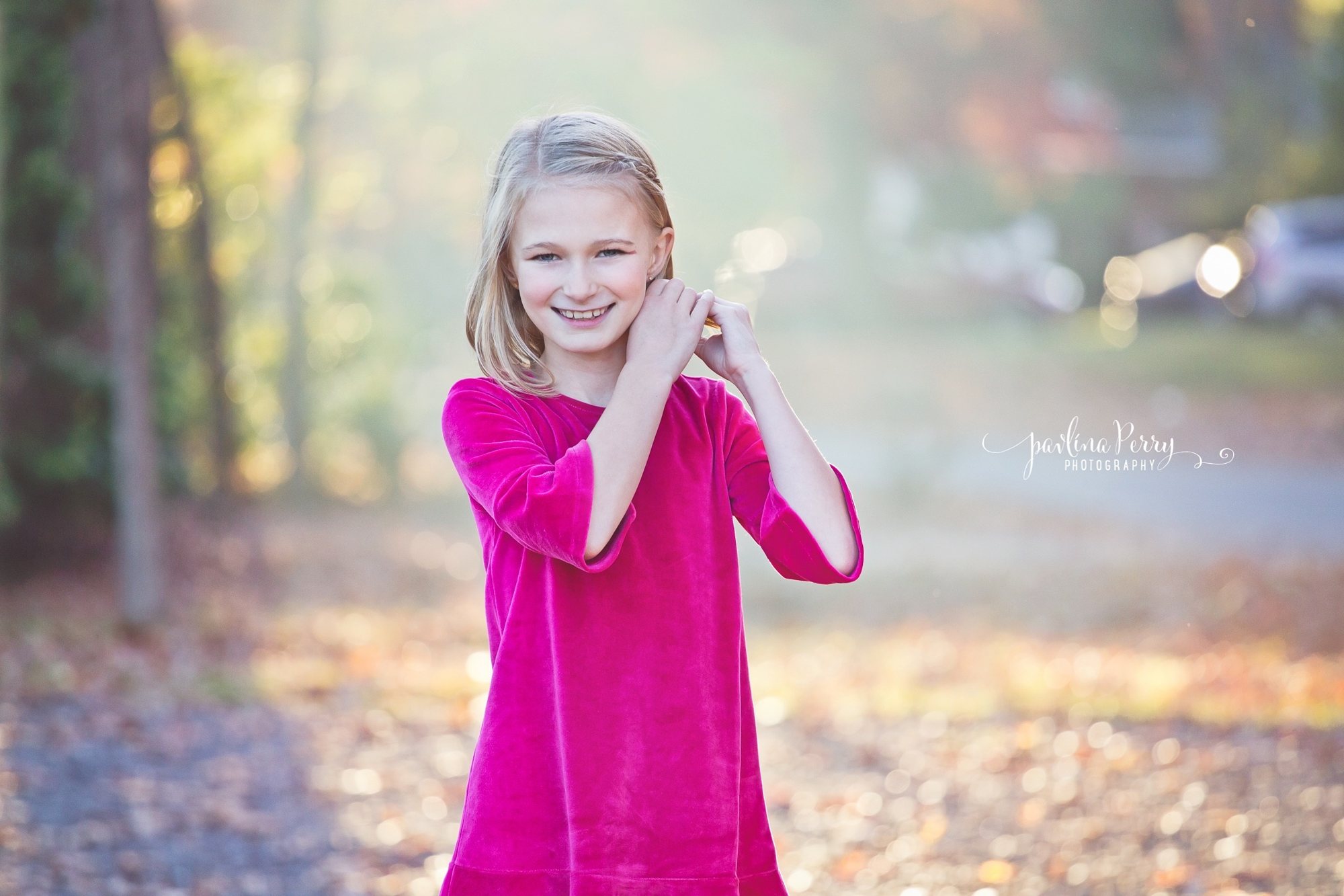 Smiling girl in a magenta dress outdoors in soft autumn light