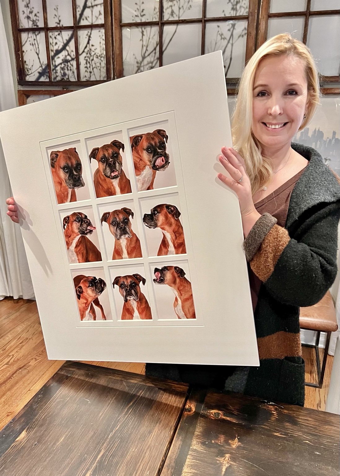 Smiling client holding a large white mat with nine expressive boxer portraits