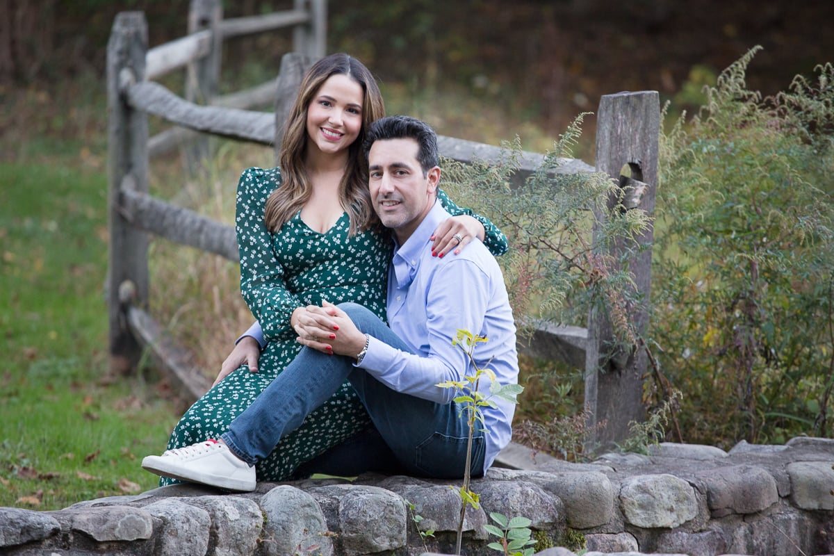 Couple sitting together beside a rustic wooden fence