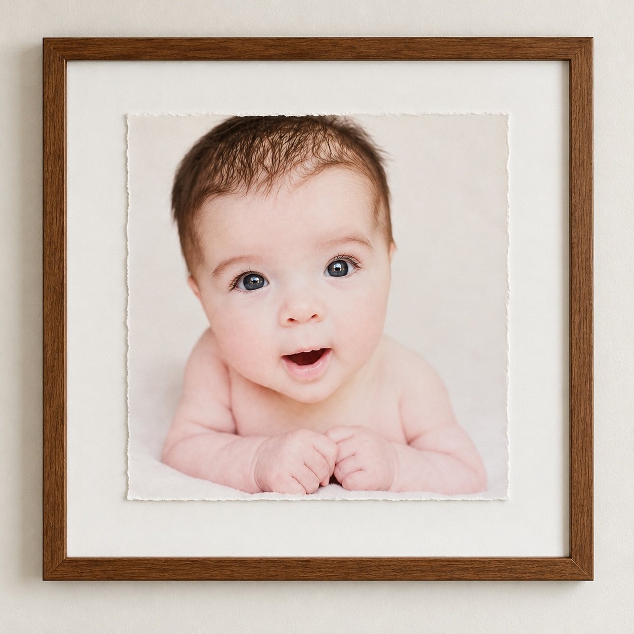 Baby portrait on deckled fine-art paper in a wooden frame with a wide ivory mat