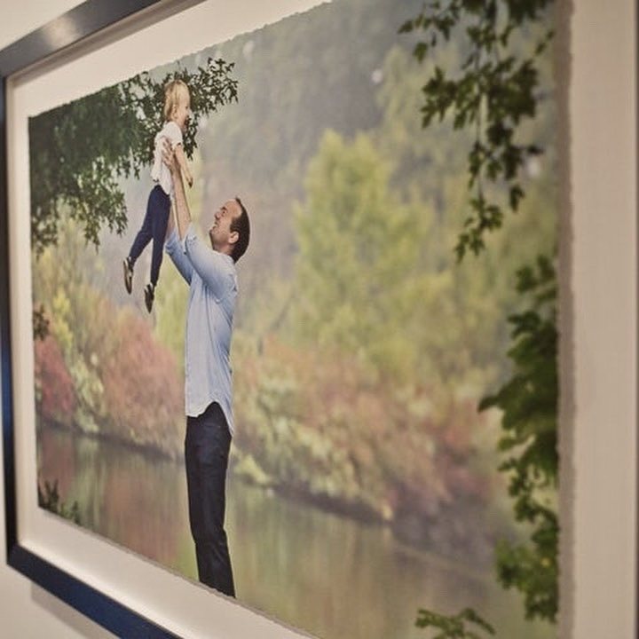 Photograph of a framed outdoor portrait of a parent lifting a child