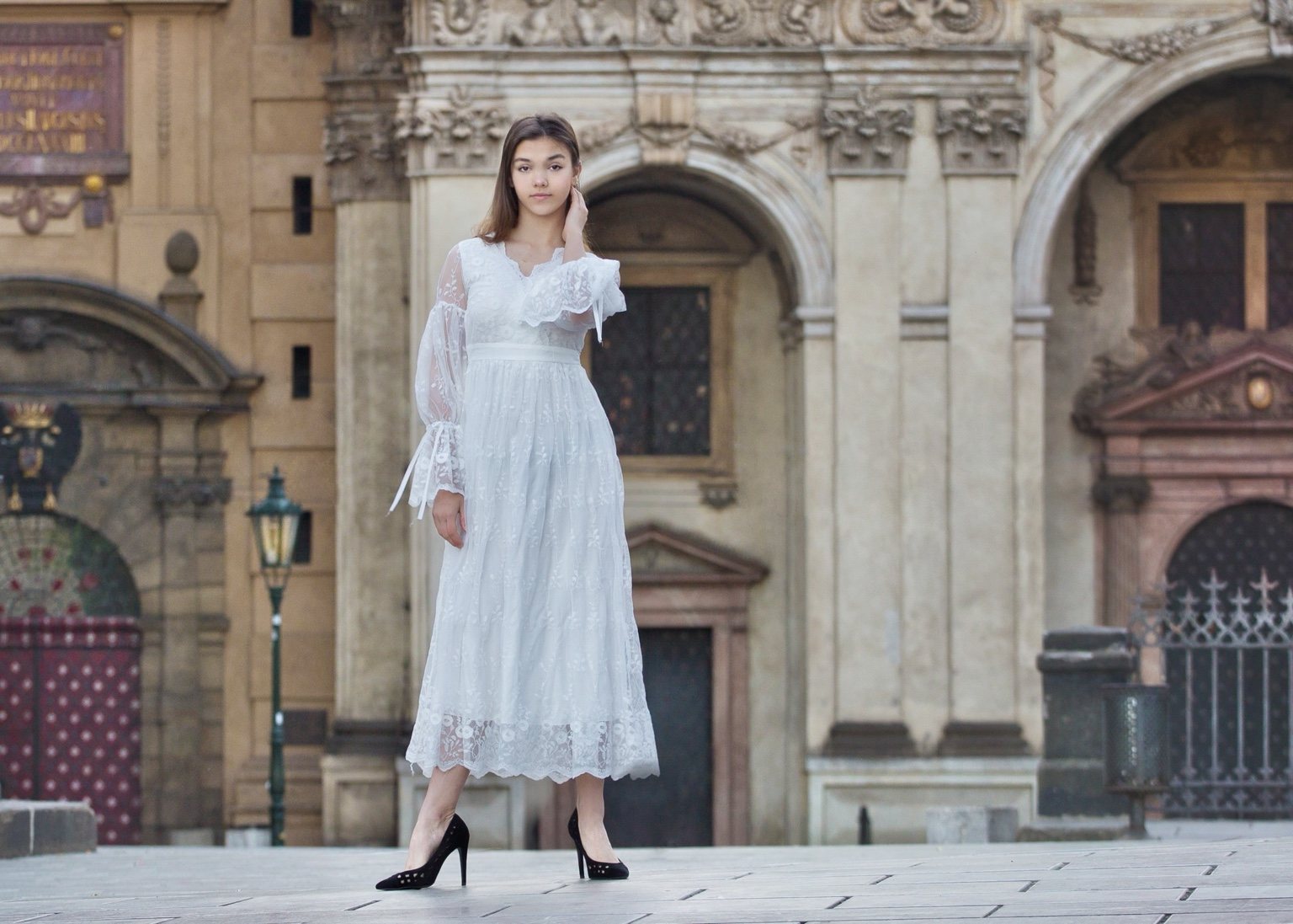 Woman in a white dress standing in front of ornate historic architecture