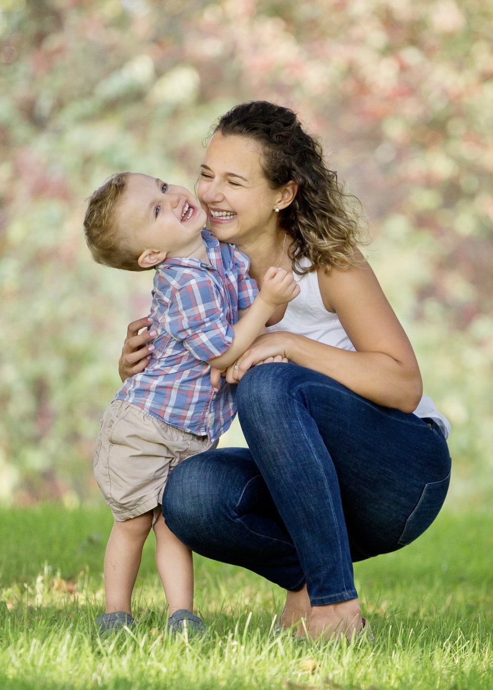 Mother and young son laughing together outdoors on the grass