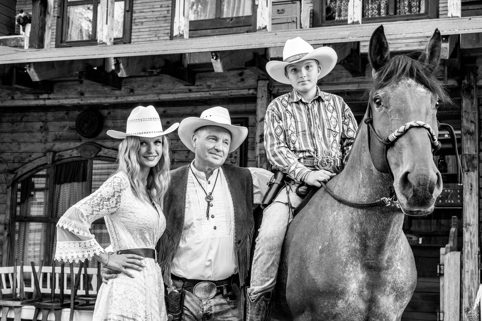 Black and white family portrait with a horse in a western town